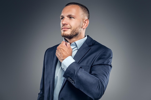 Portrait of a male dressed in a stylish blue suit over grey background.