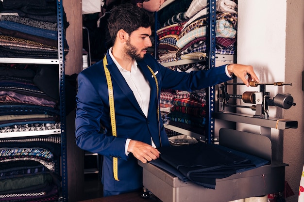 Portrait of a male fashion designer adjusting the fabric weighing scale machine in the workshop