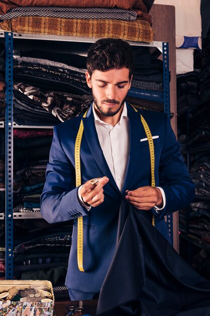 portrait of a male fashion designer sewing fabric with needle