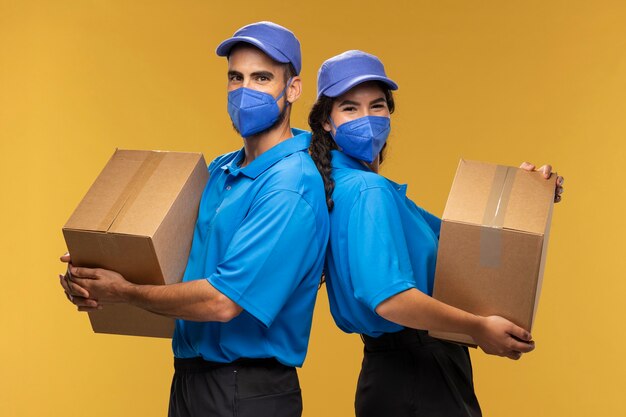 Portrait of male and female deliverers holding cardboard boxes