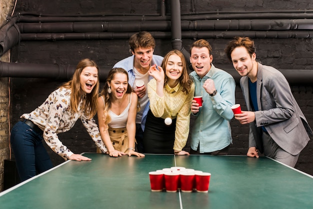 Foto gratuita ritratto degli amici maschii e femminili che giocano il pong della birra sul tavolo