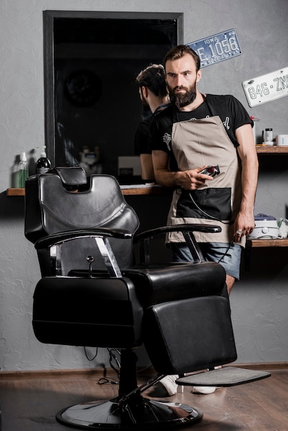 Portrait of a male hairdresser with beard standing in barber shop