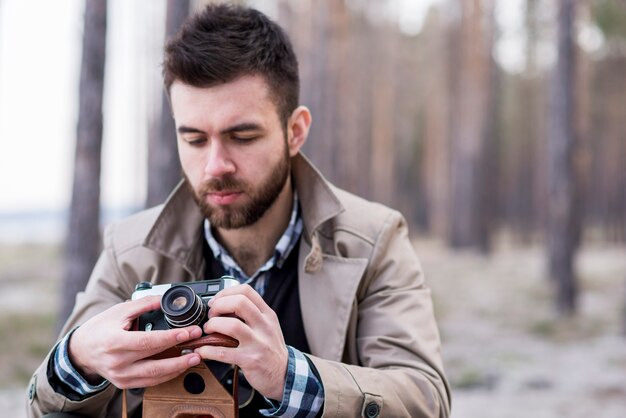 Portrait of a male hiker adjusting the camera lens