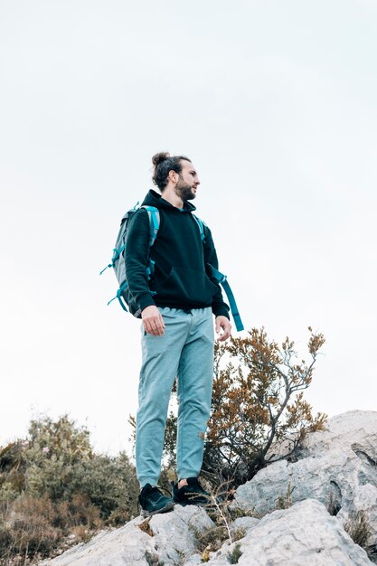 Портрет мужчины турист с его рюкзаком, стоя на скалистой горе