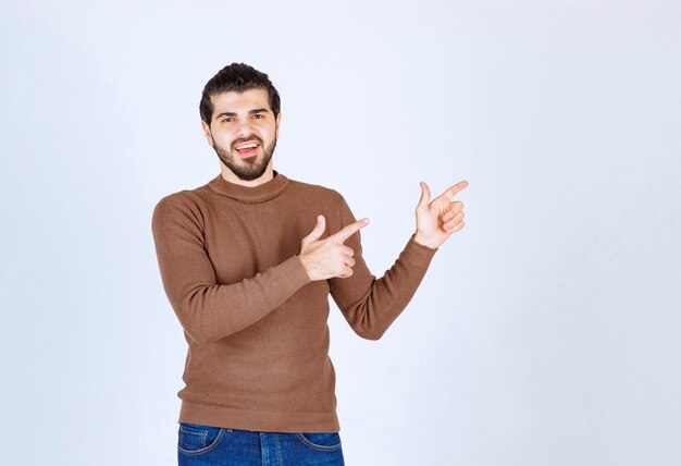Portrait of male model in brown sweater standing over white wall. High quality photo