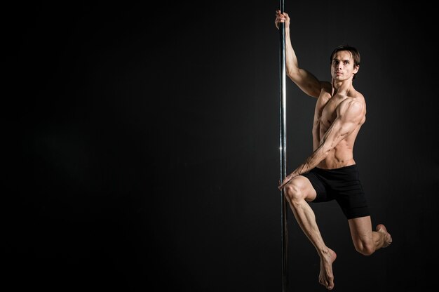 Portrait of male model performing a pole dance