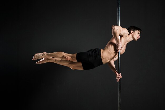 Portrait of male model performing a pole dance