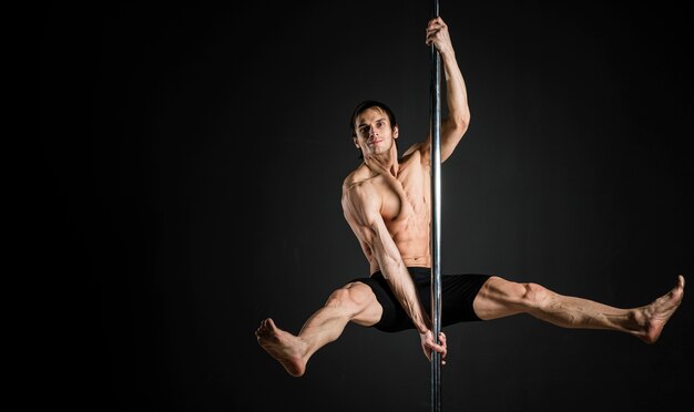 Portrait of male model performing a pole dance