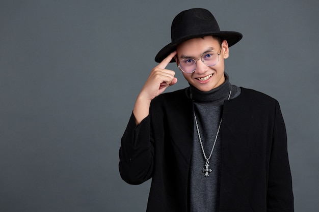 Portrait of male model pointing finger and smiling on dark  wall