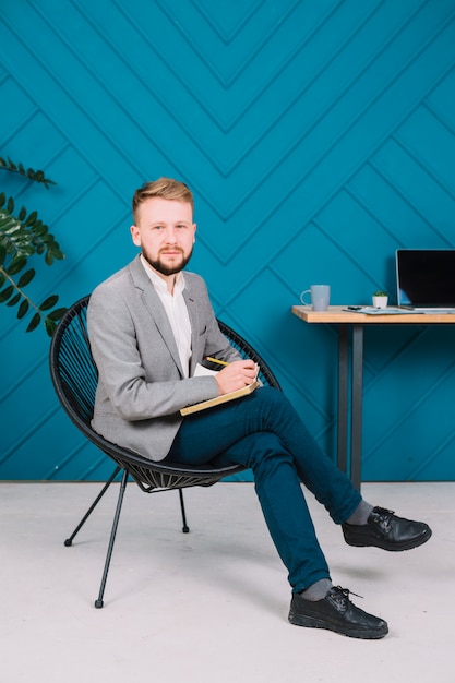 Portrait of a male psychologist writing note on diary with pencil