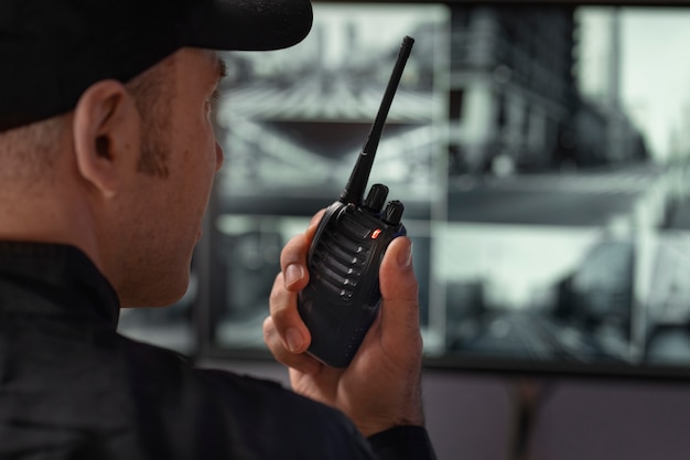 Foto gratuita ritratto di guardia di sicurezza maschile con stazione radio e schermi della fotocamera