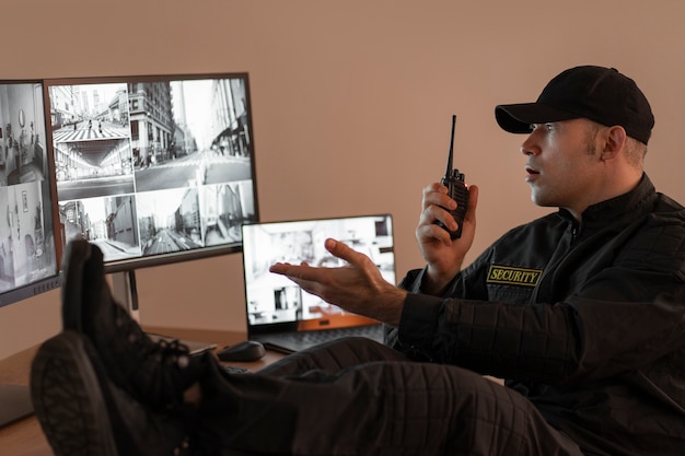 Foto gratuita ritratto di guardia di sicurezza maschile con stazione radio e schermi della fotocamera