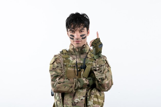 Portrait of male soldier in camouflage ready to fight on white wall