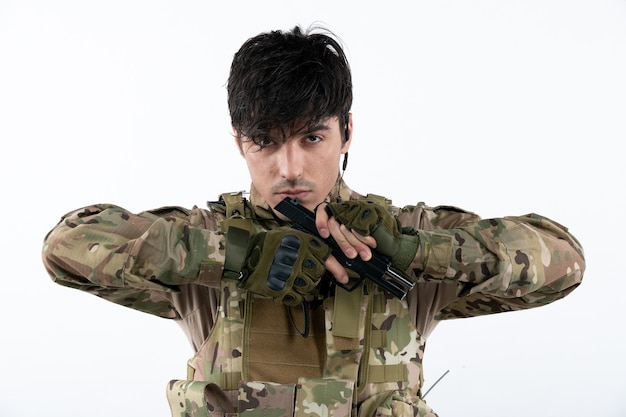 Portrait of male soldier fighting during operation with gun white wall