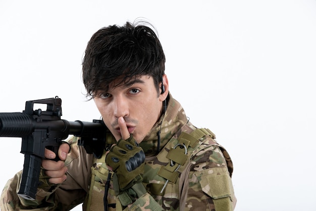 Portrait of male soldier fighting during war with machine gun white wall