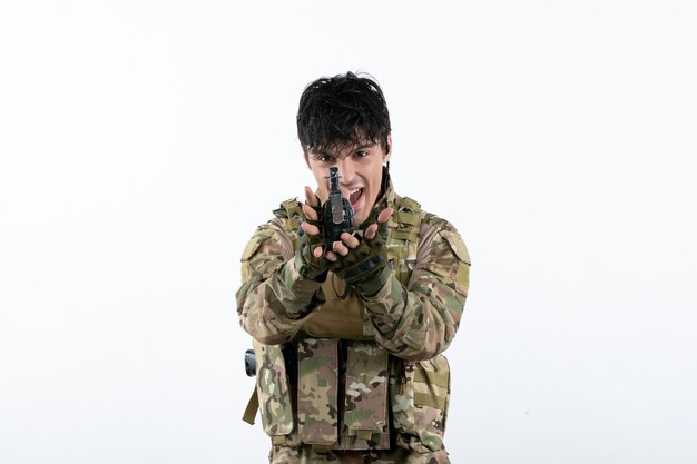 Portrait of male soldier in military uniform with grenade on white wall