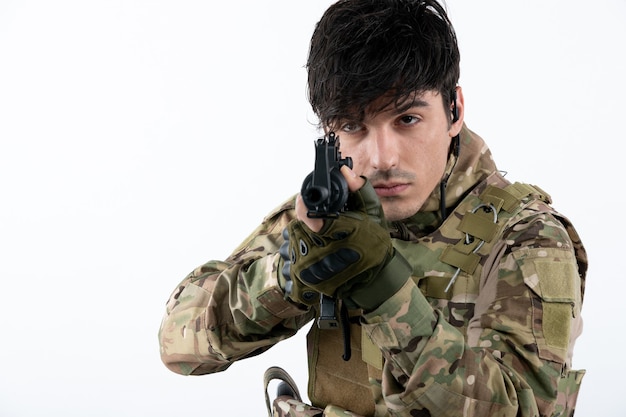 Portrait of male soldier in military uniform with machine gun white wall