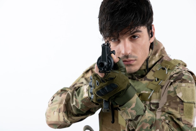 Portrait of male soldier in military uniform with machine gun white wall