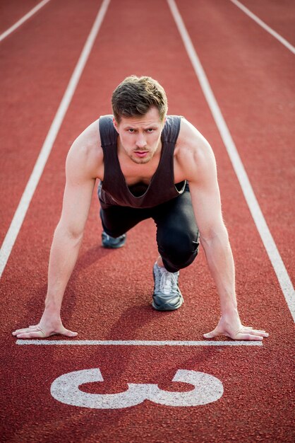 Portrait of a male sprinter ready for race on racetrack