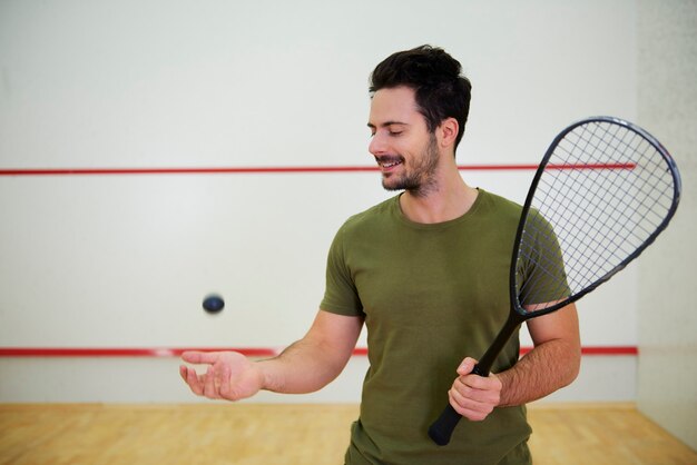 Portrait of male squash player with racket on court