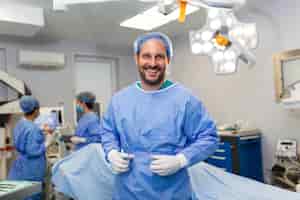 Foto gratuita ritratto di chirurgo maschile in sala operatoria guardando la fotocamera dottore in scrub e maschera medica nella moderna sala operatoria ospedaliera