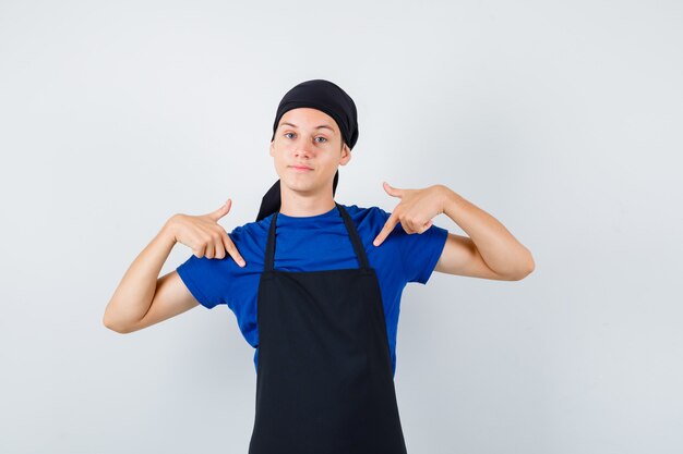 Tシャツ、エプロン、自信を持って正面から自分を指して10代の男性料理人の肖像画