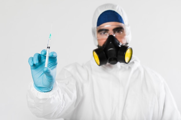 Portrait of male with face mask holding syringe