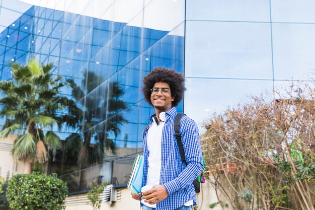 大学の建物の前に立っている男性の若い学生の肖像画
