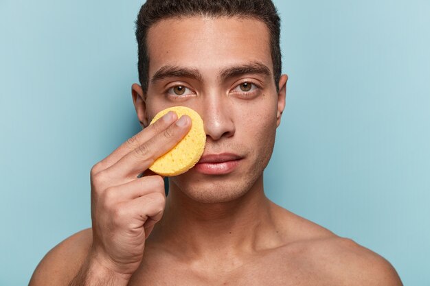 Portrait of man cleaning his face with sponge