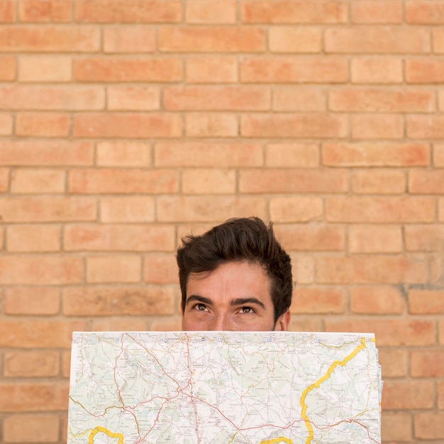 Free photo portrait of a man covering face with a map