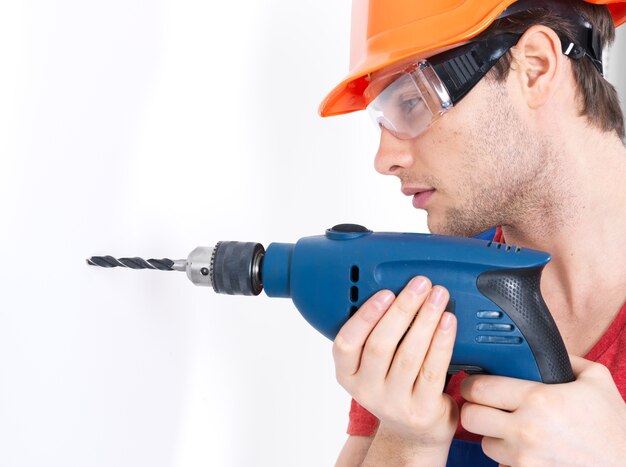 Portrait of a man drilling a hole in the wall.