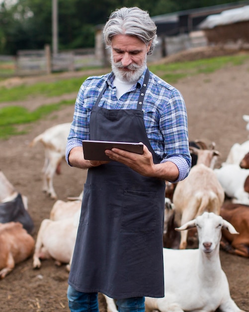 Foto gratuita uomo del ritratto all'azienda agricola che osserva sulla compressa