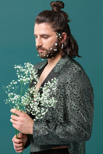 Портрет мужчины в модной одежде с цветами в руках