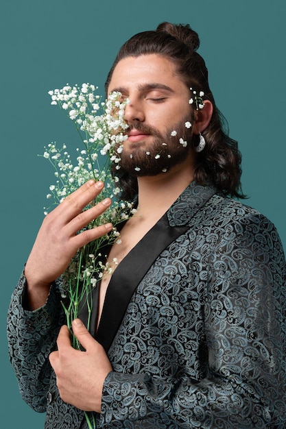 Foto gratuita uomo del ritratto in vestiti alla moda che tengono i fiori