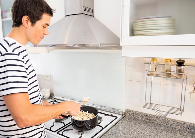 Portrait of man frying popcorn in sauce pan in the kitchen