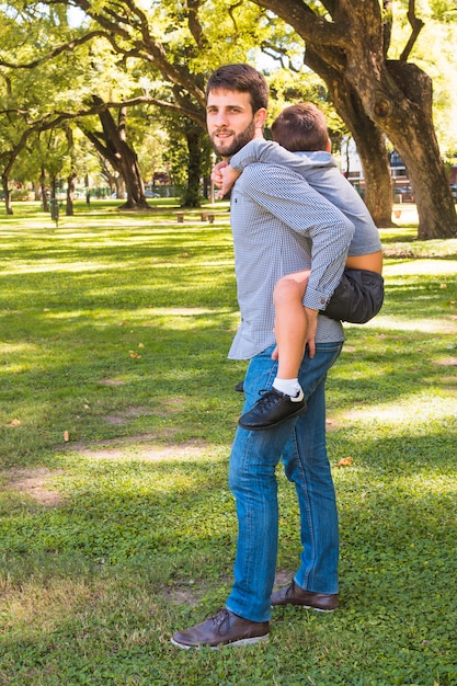 Foto gratuita ritratto di un uomo che dà sulle spalle giro nel parco