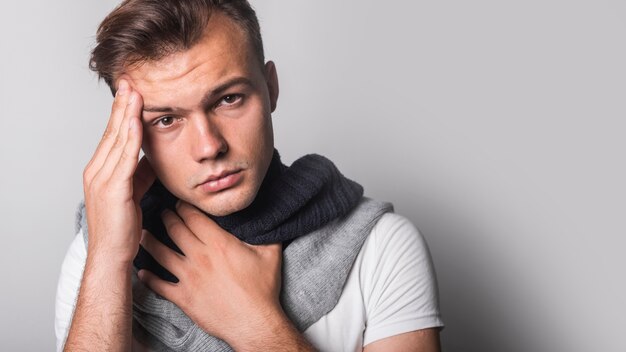 Portrait of man having headache against gray background