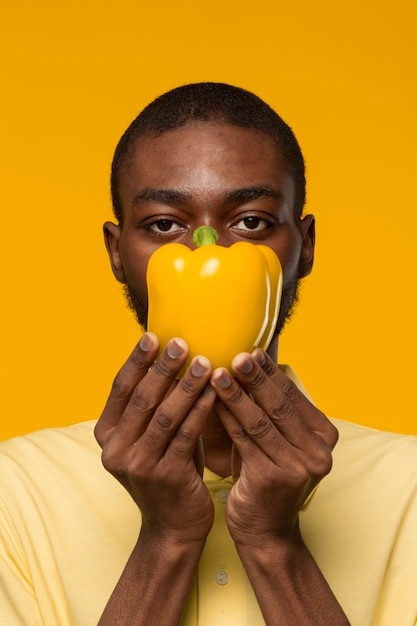 Portrait of man holding bell pepper near his face