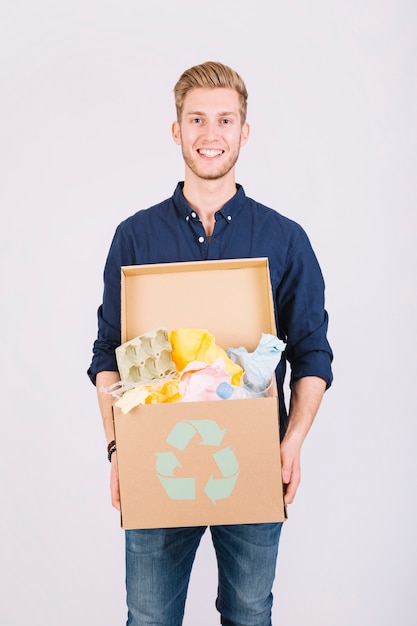 Free photo portrait of a man holding cardboard box full of garbage with recycle icon