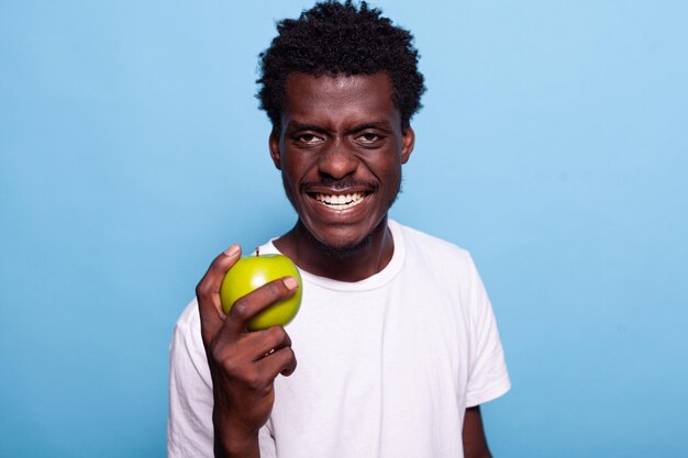 Портрет мужчины, держащего в руке зеленое яблоко и смотрящего в камеру