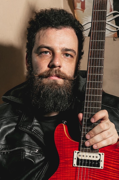 Portrait of man holding red guitar