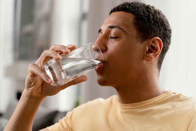 Free photo portrait man at home drinking glass of water