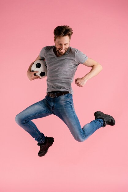 portrait man jumping holding football ball