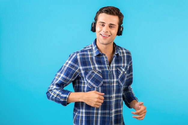 Портрет мужчины, слушающего музыку в беспроводных наушниках, веселится на синем