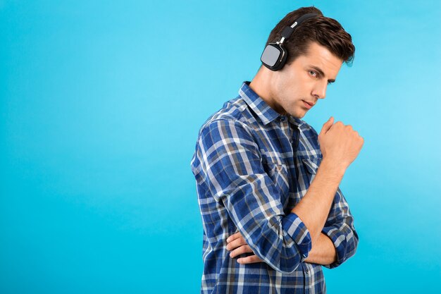 Portrait of man listening to music on wireless headphones having fun on blue