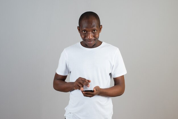 Portrait of man looking at cellphone on gray wall