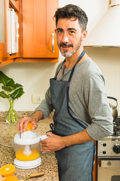 Portrait of a man making orange juice in the kitchen