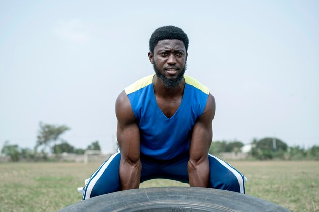 Portrait man in nature lifting truck wheel