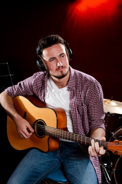 Free photo portrait of a man playing guitar and wearing headphones