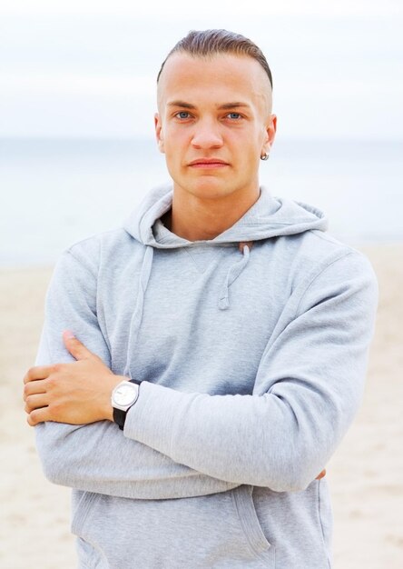 Portrait of man posing on the beach in a grey coat